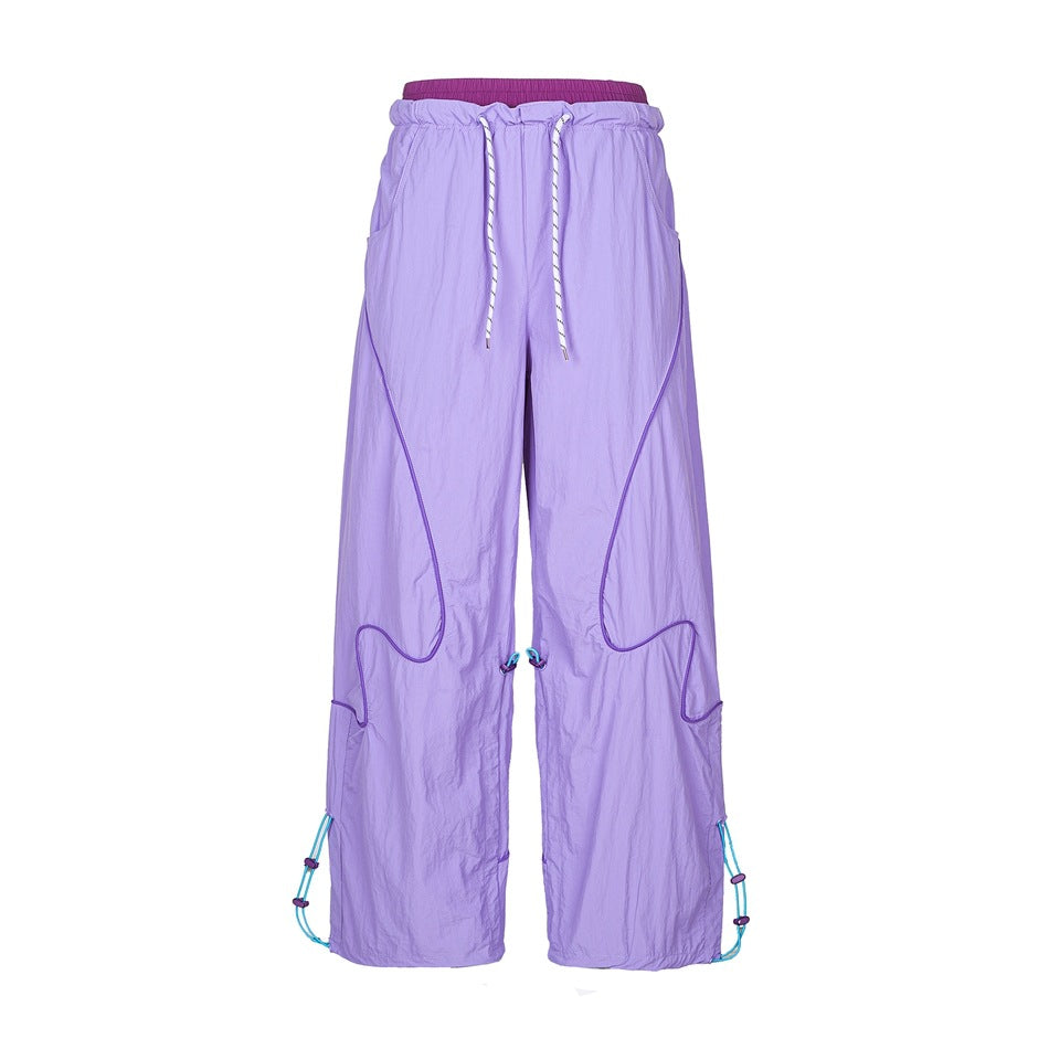 Lavender purple wide-leg pants with deep purple inner waistband, wavy piping and turquoise toggle cords, front view