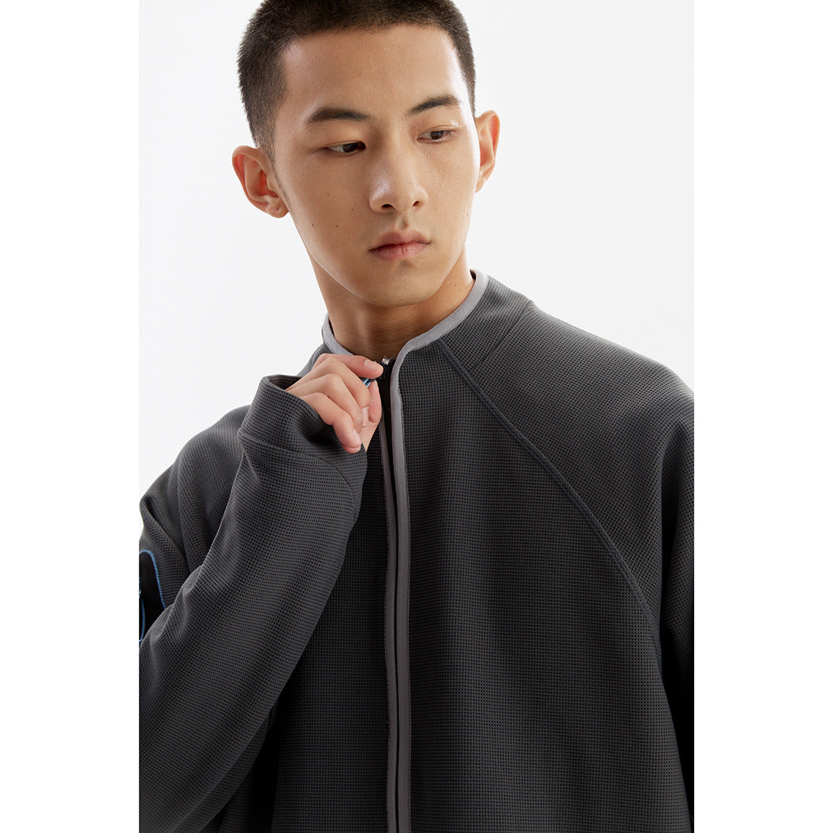 Close-up of a model wearing a charcoal textured jacket with a gray-trimmed collar and front zipper.