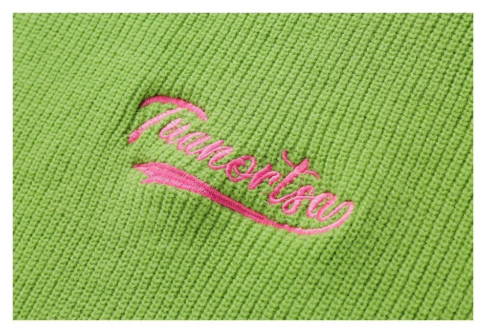 Close-up of lime-green ribbed knit with pink cursive embroidery and an underline.