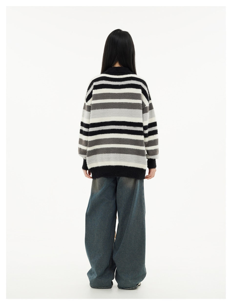 Rear view of a model wearing an oversized black, white, and gray striped sweater with wide-leg blue jeans.