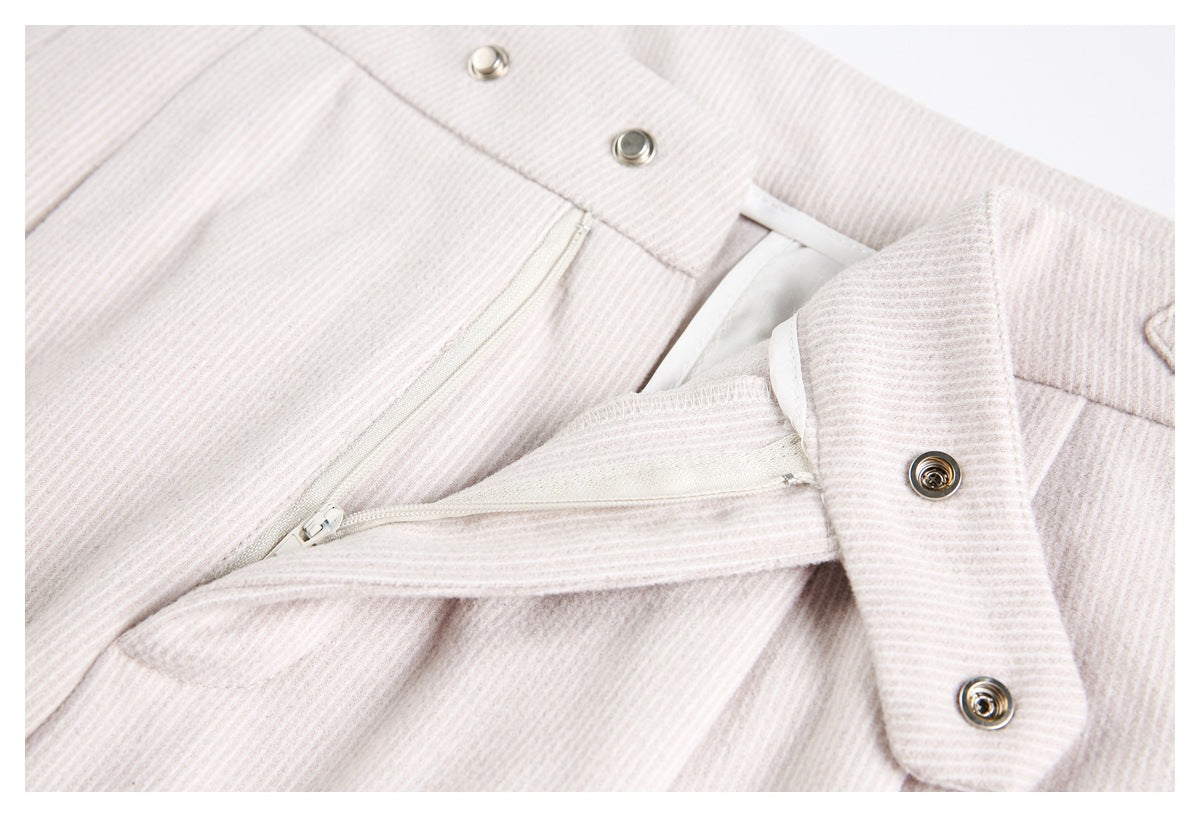 Close-up of the open fly and zipper on pale beige ribbed trousers.
