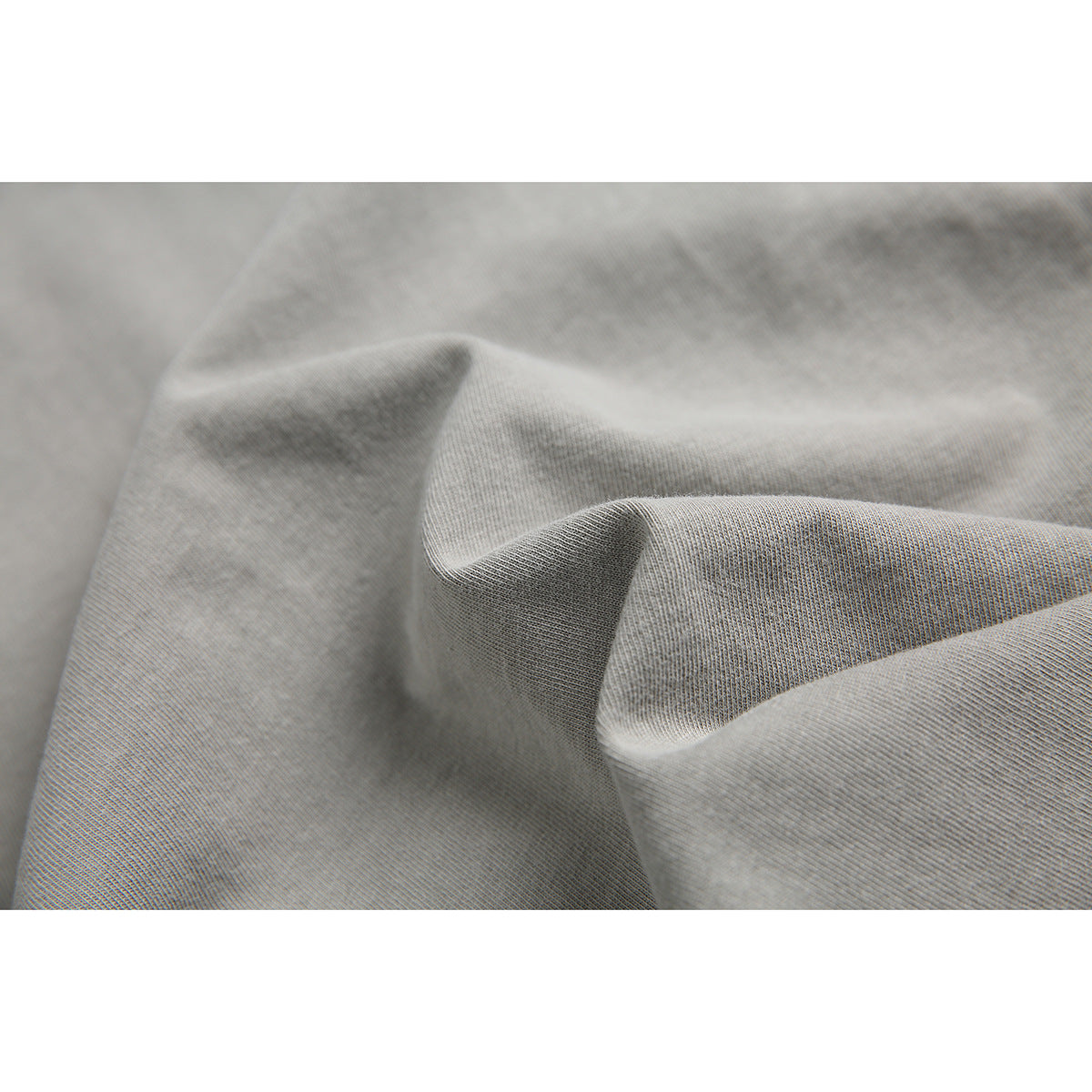 Macro view of light gray fabric draped to show its fine knit texture.