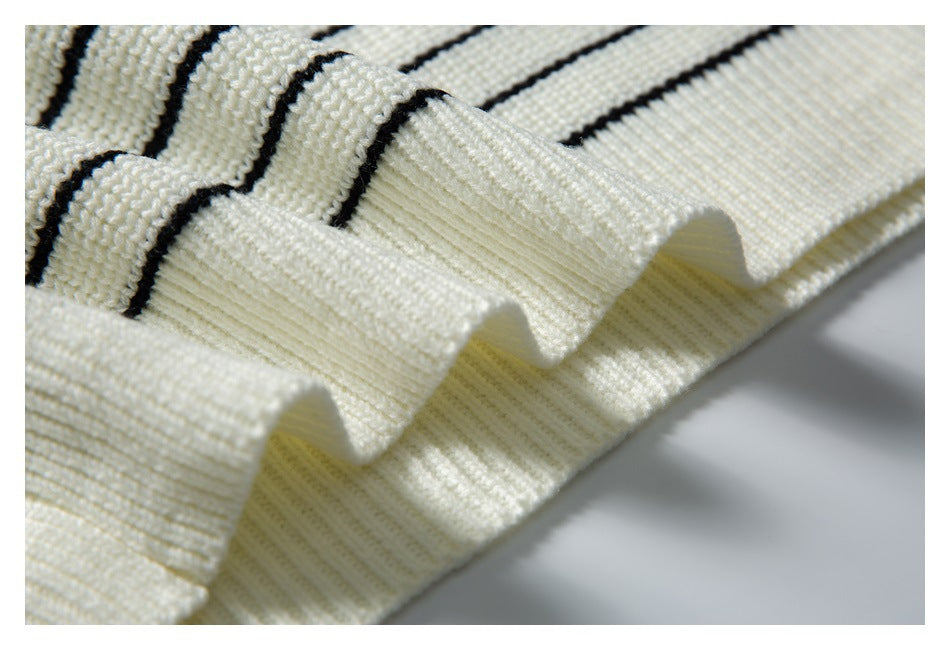 Close-up of a ribbed ivory garment edge with narrow black stripes and folded fabric.