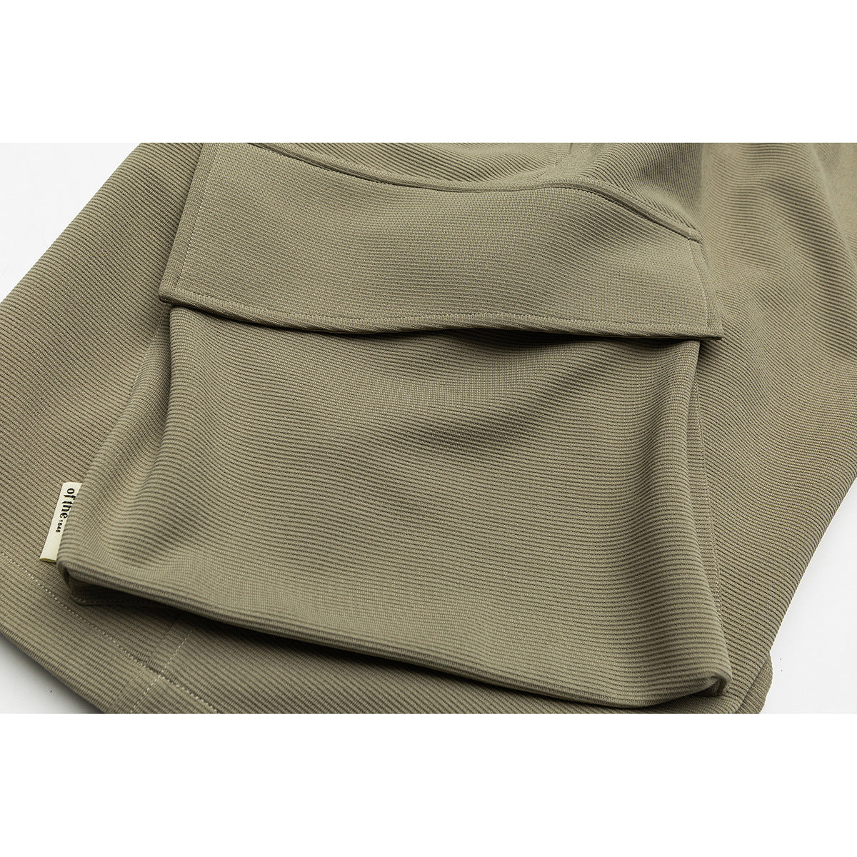 Close-up of olive-khaki pants with a large flap pocket and a small sewn label.