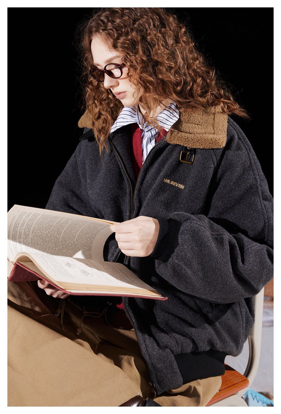 Model seated in a charcoal zip-up jacket with a tan fleece collar and black ribbed cuffs.