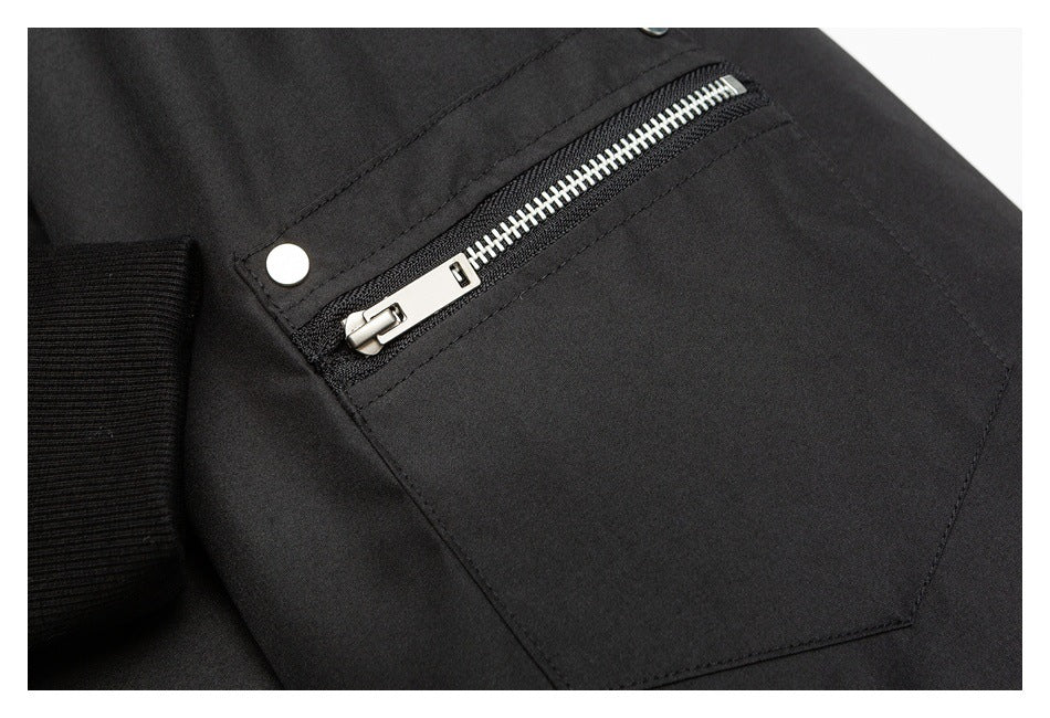 Close-up of a black jacket pocket with a silver zipper and snap fastener.