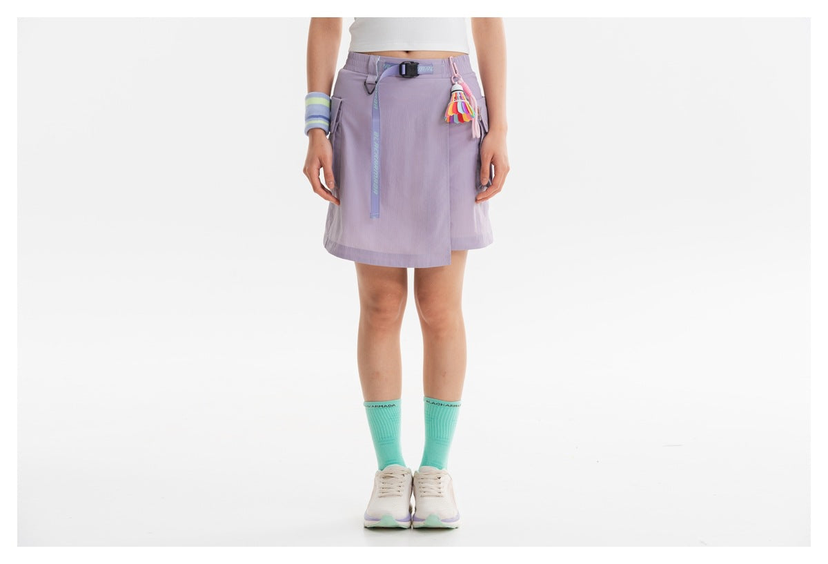 Front view of a model wearing a lilac wrap-style cargo skirt with a black belt and colorful hanging tassel.