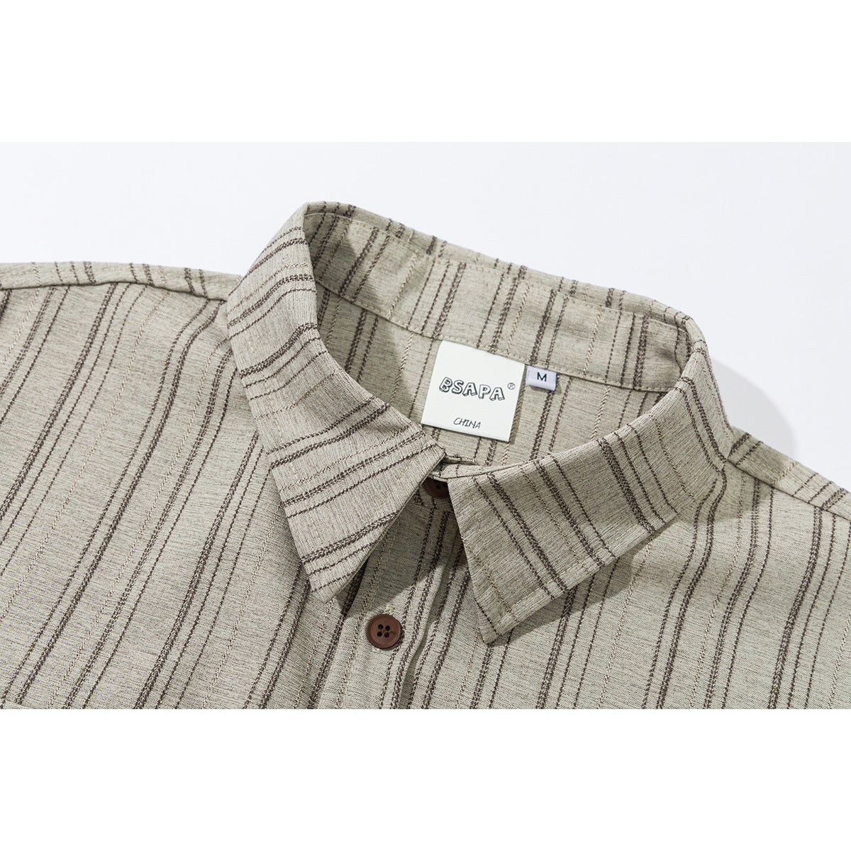 Close-up of a beige striped shirt collar, brown button, and sewn neck label.