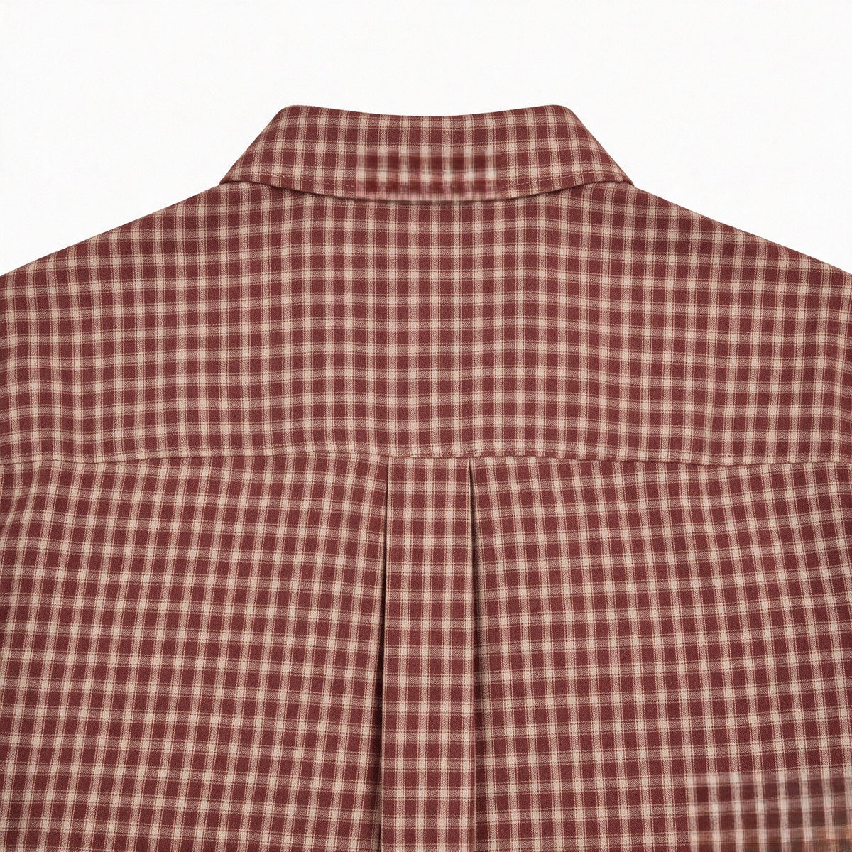 Close-up of the rust-red and cream plaid shirt's back collar and yoke seam.