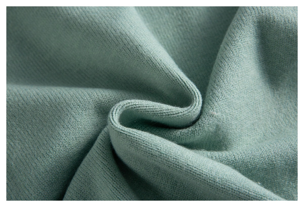 Close-up of the pale sage-green knit fabric, folded to show its texture and edge stitching.