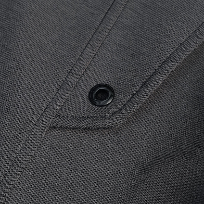 Close-up of a black snap fastener on a charcoal T-shirt seam.