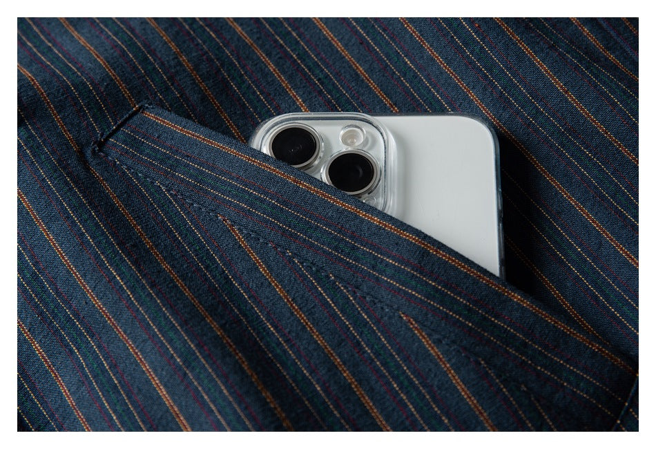 Close-up of a pocket in dark blue multicolor-striped fabric holding a white smartphone.