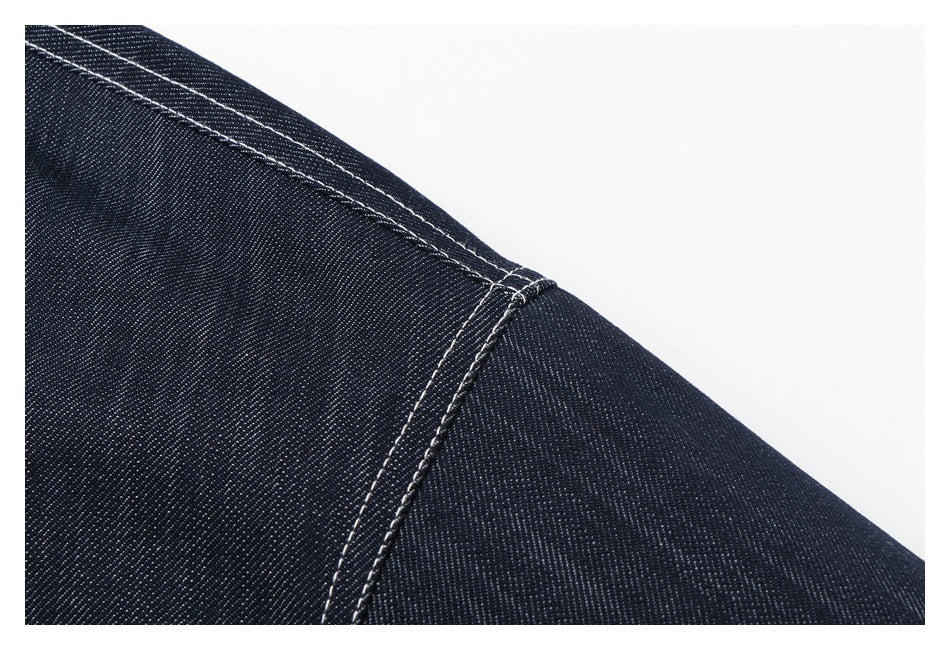 Close-up of a dark denim seam with contrasting double rows of white stitching.