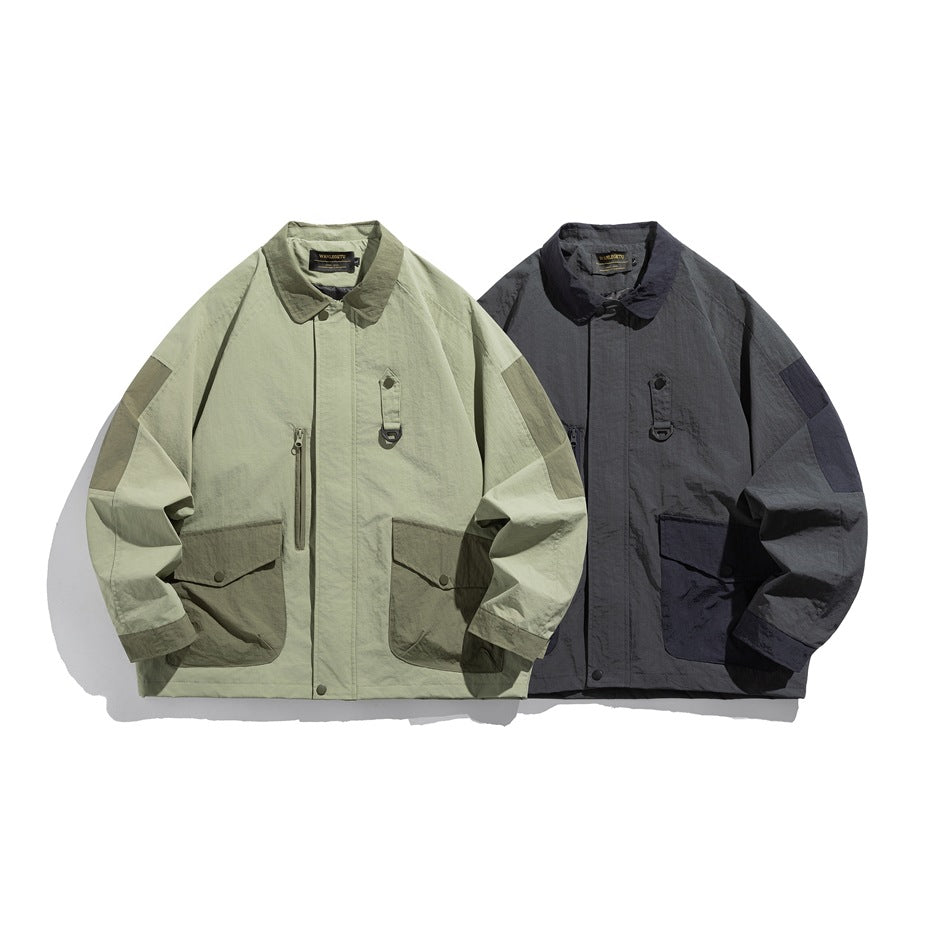Front view of two jackets with pointed collars, flap pockets, and sleeve panels, in light olive and charcoal gray.