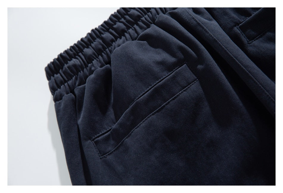 Close-up of dark navy pants showing a slanted pocket opening and gathered waistband.