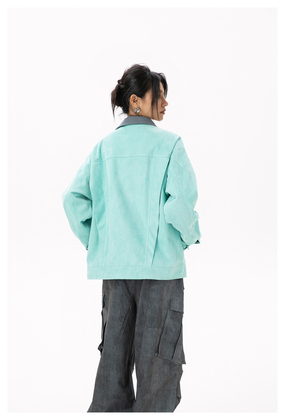 Back view of a model wearing a mint jacket with a gray collar and charcoal cargo pants.