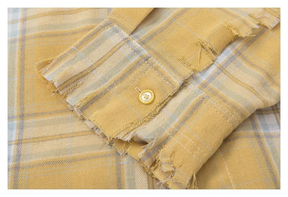 Close-up of a shirt cuff with a yellow button and distressed frayed edges.