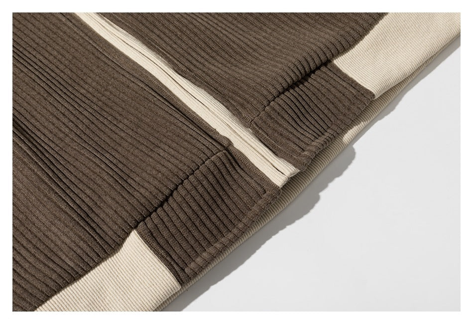 Close-up of brown ribbed garment panels and seams with cream trim and a banded edge.