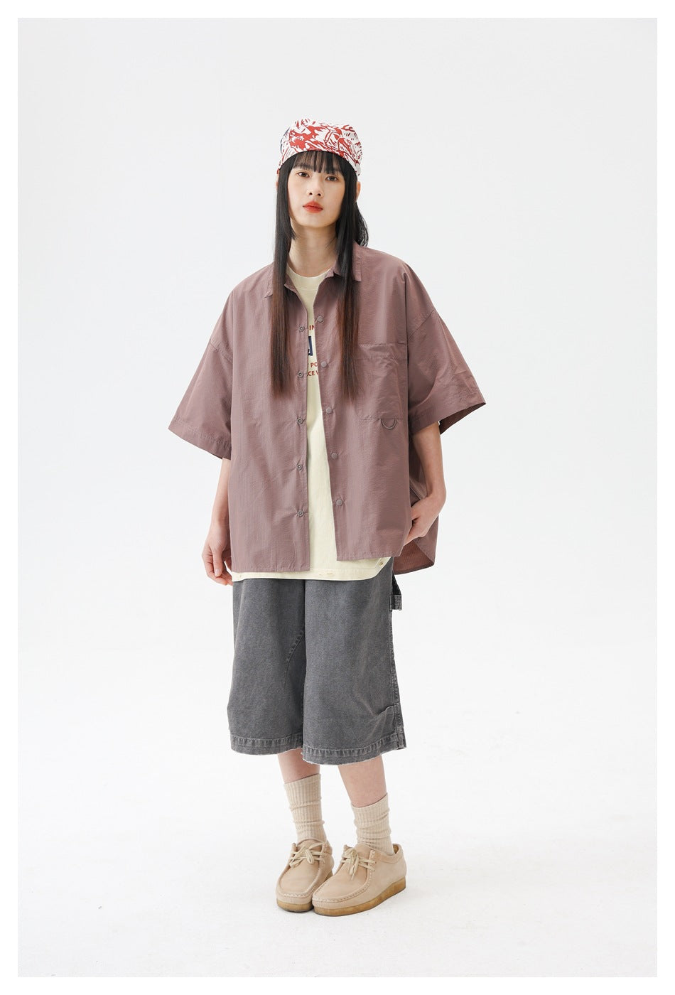 Model wearing a dusty rose oversized short-sleeve button-up shirt with a chest pocket, over a cream top.