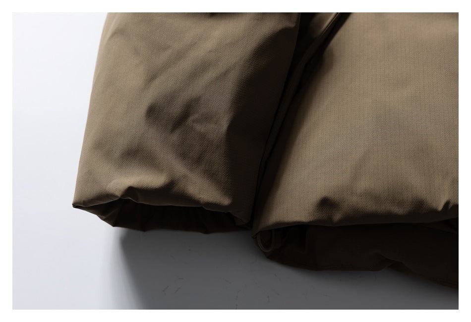 Close-up of overlapping brown jacket fabric and a folded hem against a white background.