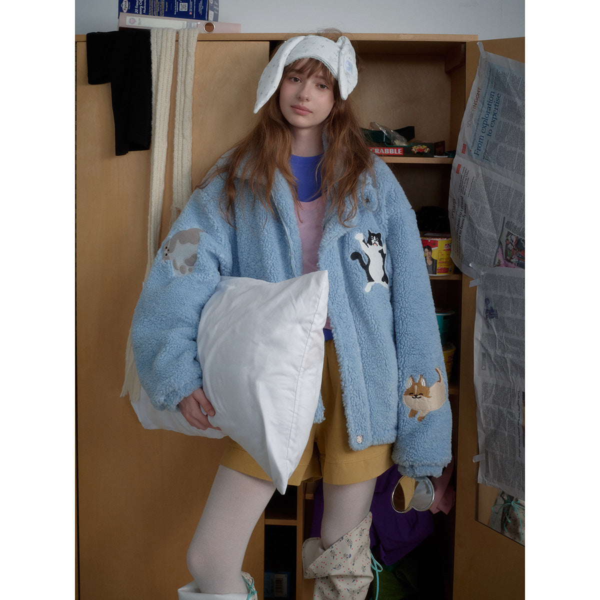 Front view of a model wearing a light blue plush jacket with animal appliqués and a high collar.