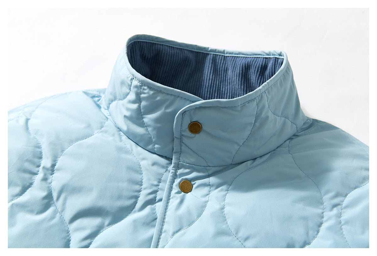 Close-up of a light blue quilted jacket's high collar, dark ribbed lining, and brass-tone snap buttons.