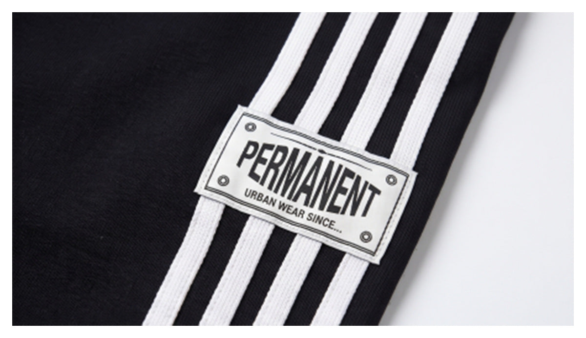 Close-up of black fabric with three white stripes and a rectangular “PERMANENT” label.