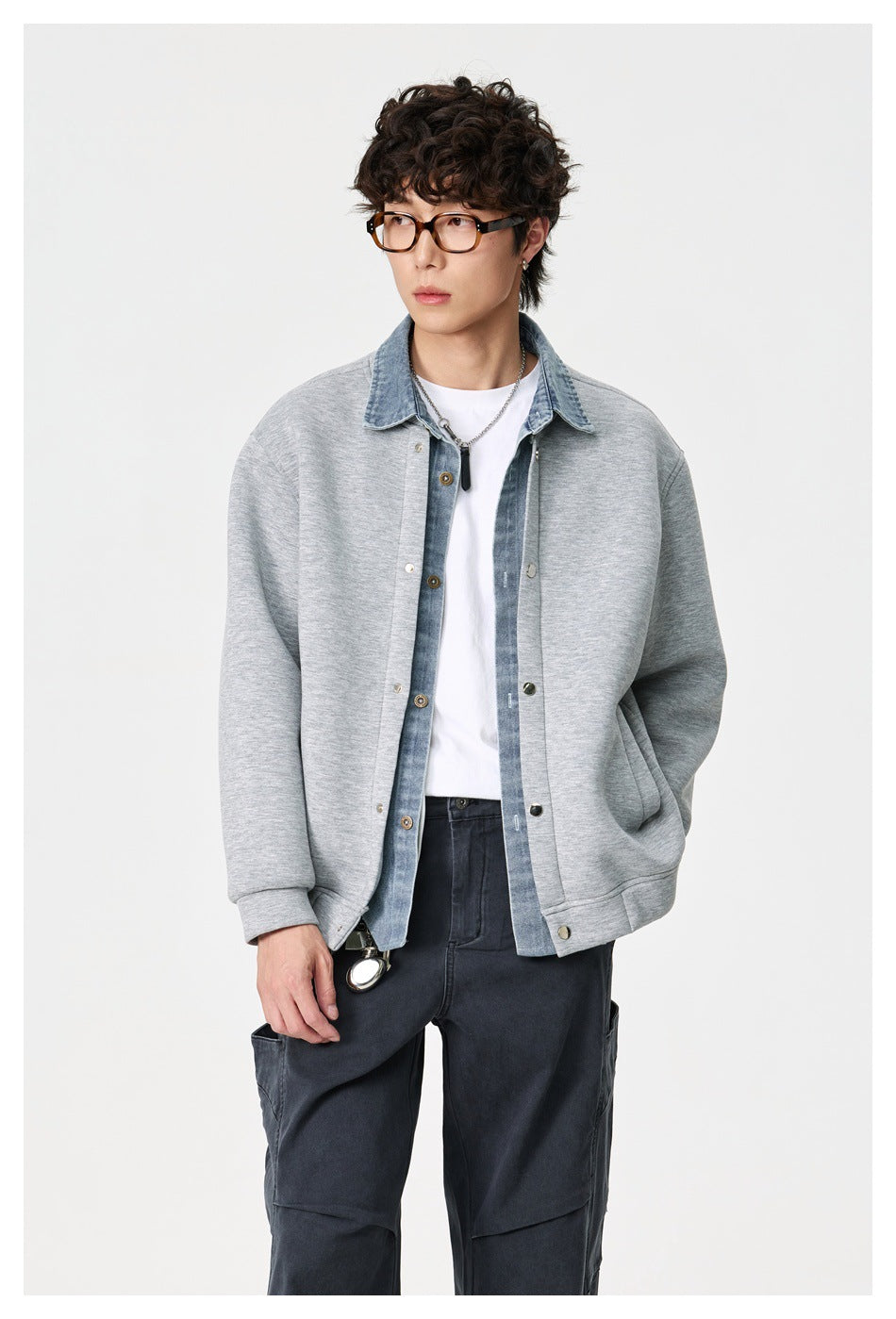 Model wearing a light gray snap-front jacket with a blue denim collar and placket, white tee, and dark cargo pants.