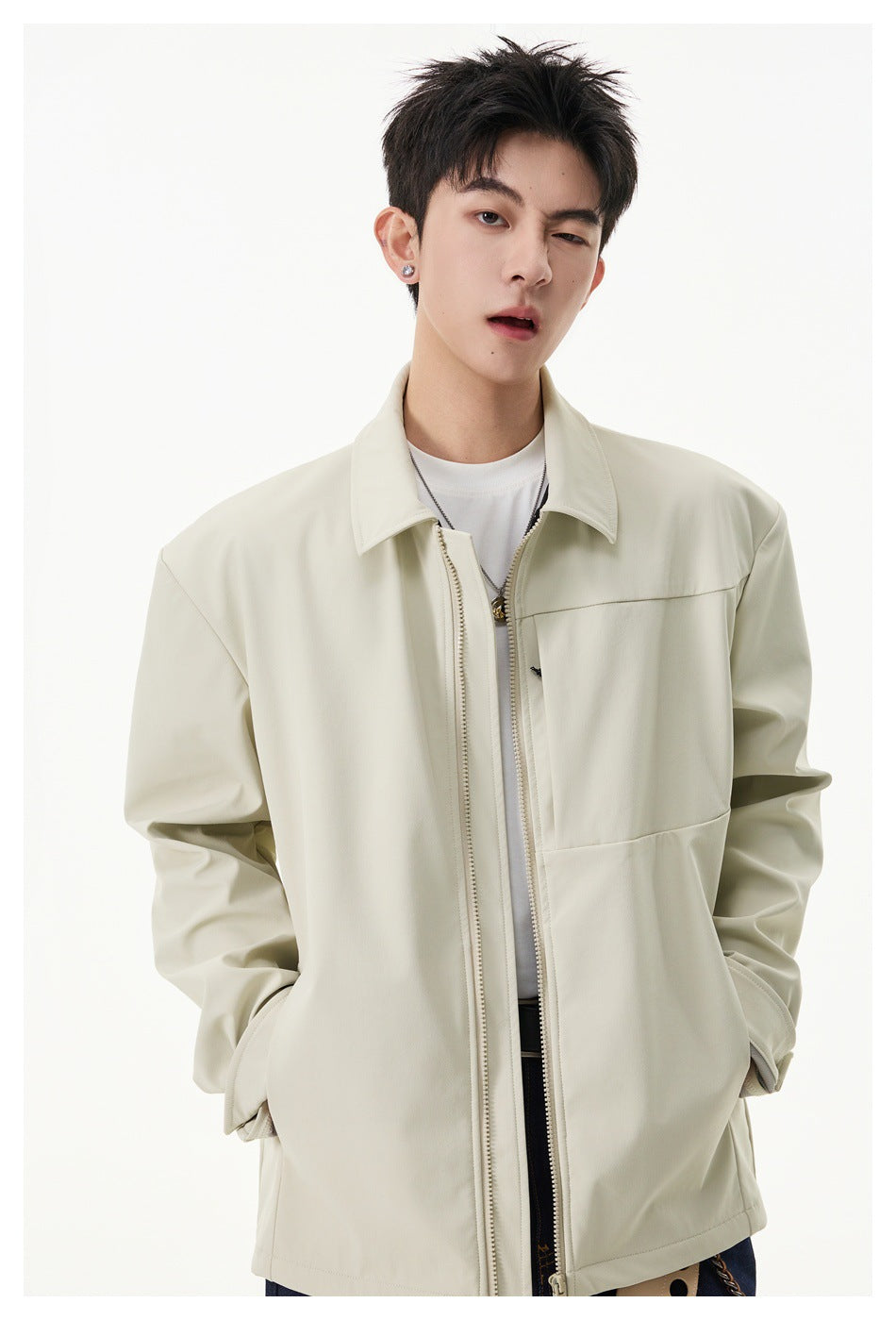 Close view of a model wearing an ivory jacket with a pointed collar, front zipper and chest panel.