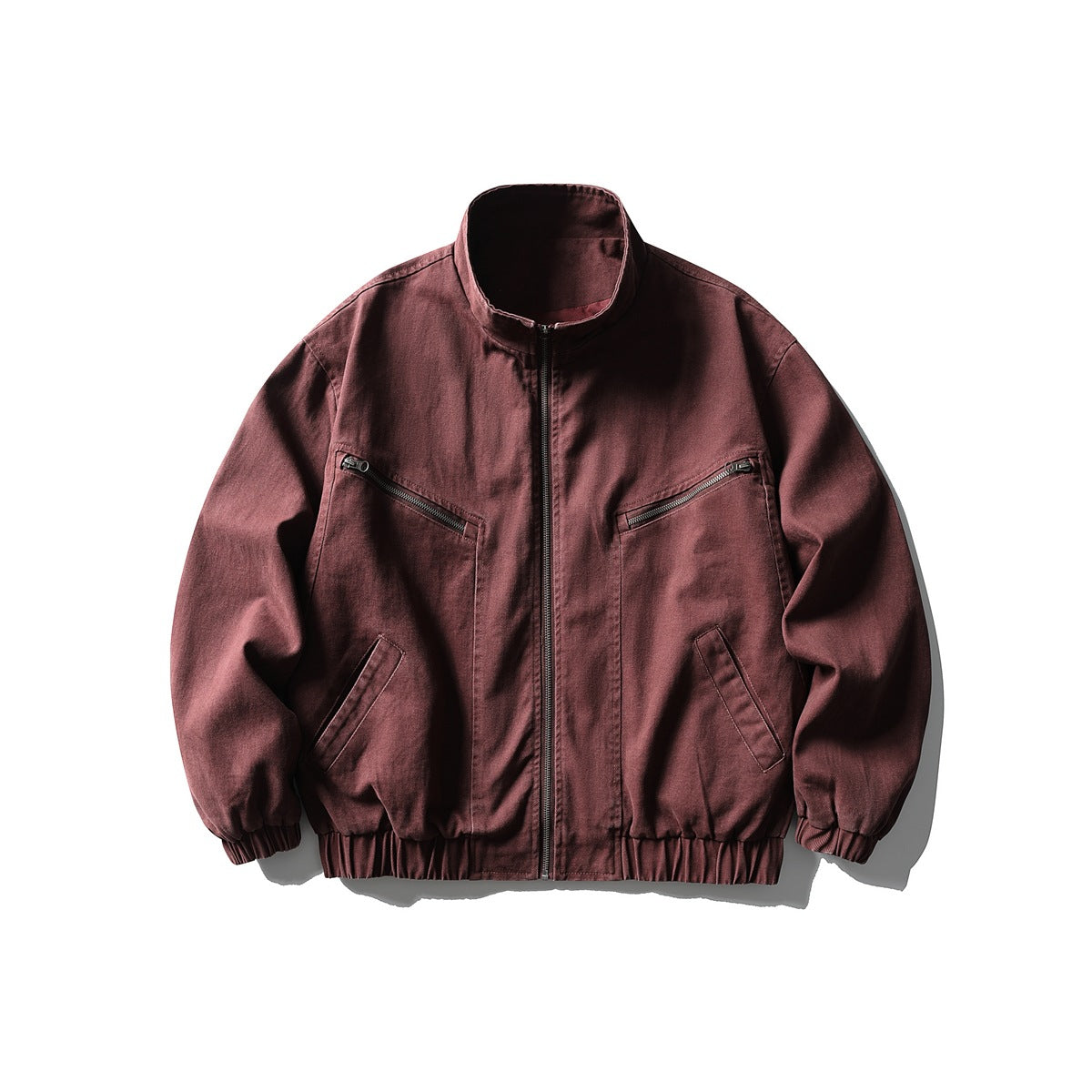 Wine red stand-collar zip jacket with zippered chest pockets and elastic cuffs and hem, flat lay front view