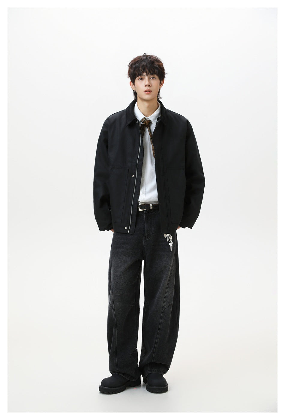 Model wearing a black zip-front collared jacket with a white shirt, plaid tie and wide-leg black jeans