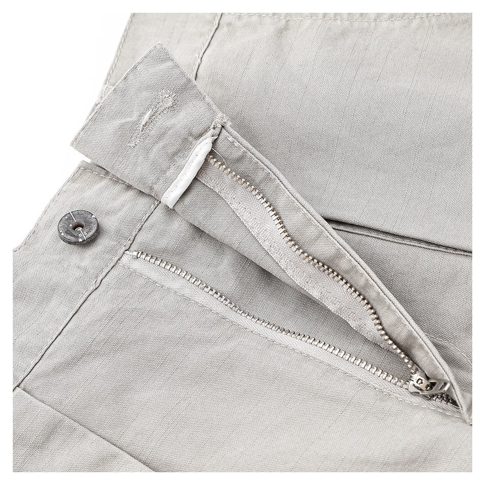 Close-up of the trousers' open fly, metal zipper, and waistband button.