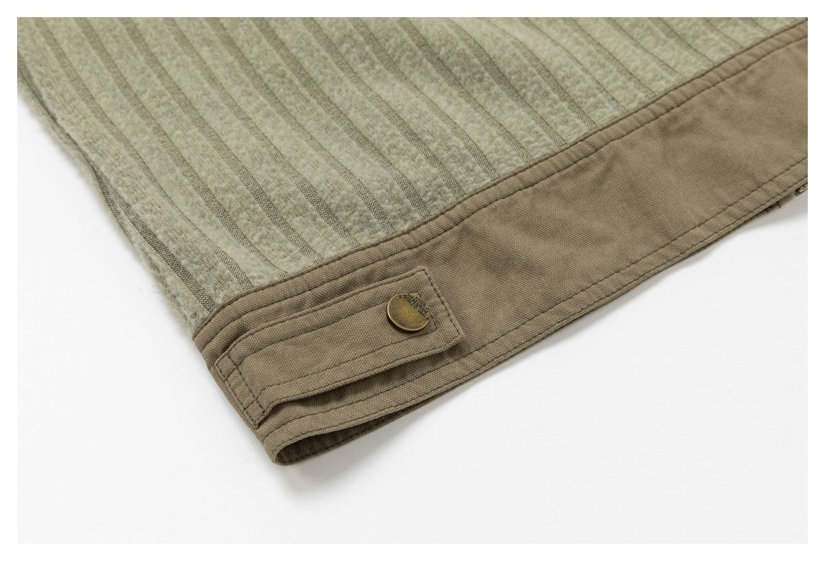 Close-up of a beige striped garment hem with a brown cuff tab and brass-colored button.