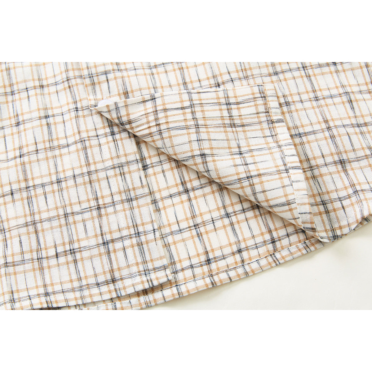 Close-up of the cream plaid shirt's buttoned chest pocket and fabric pattern.