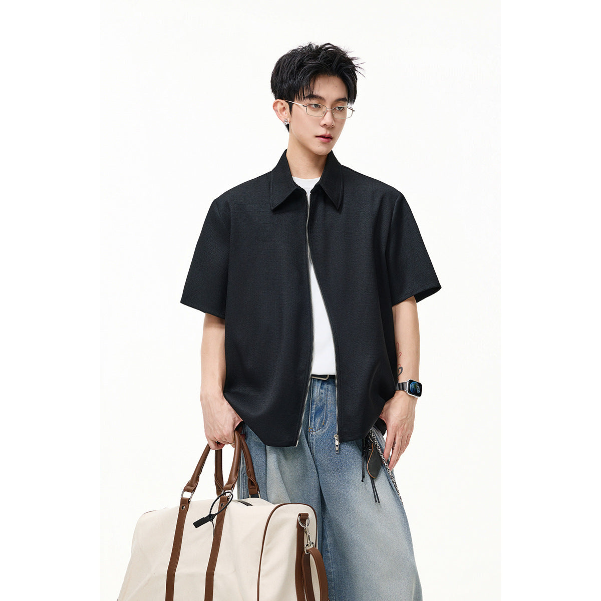 Model wearing a black short-sleeve collared zip-front shirt over a white tee, with light blue jeans.