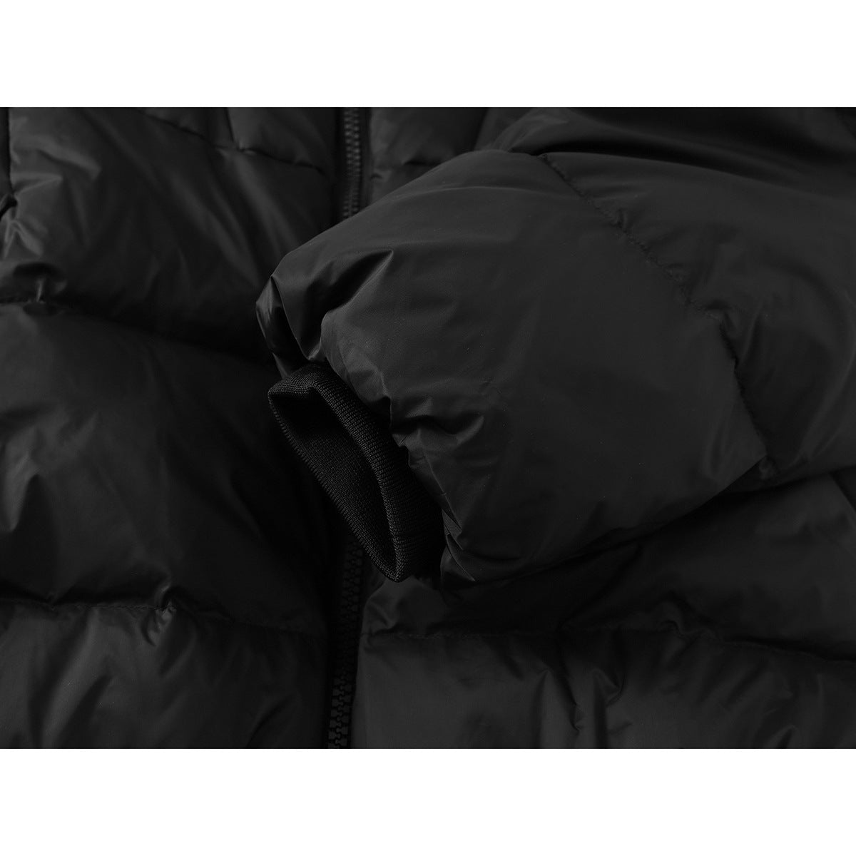 Close-up of a black puffer jacket sleeve cuff beside the front zipper.