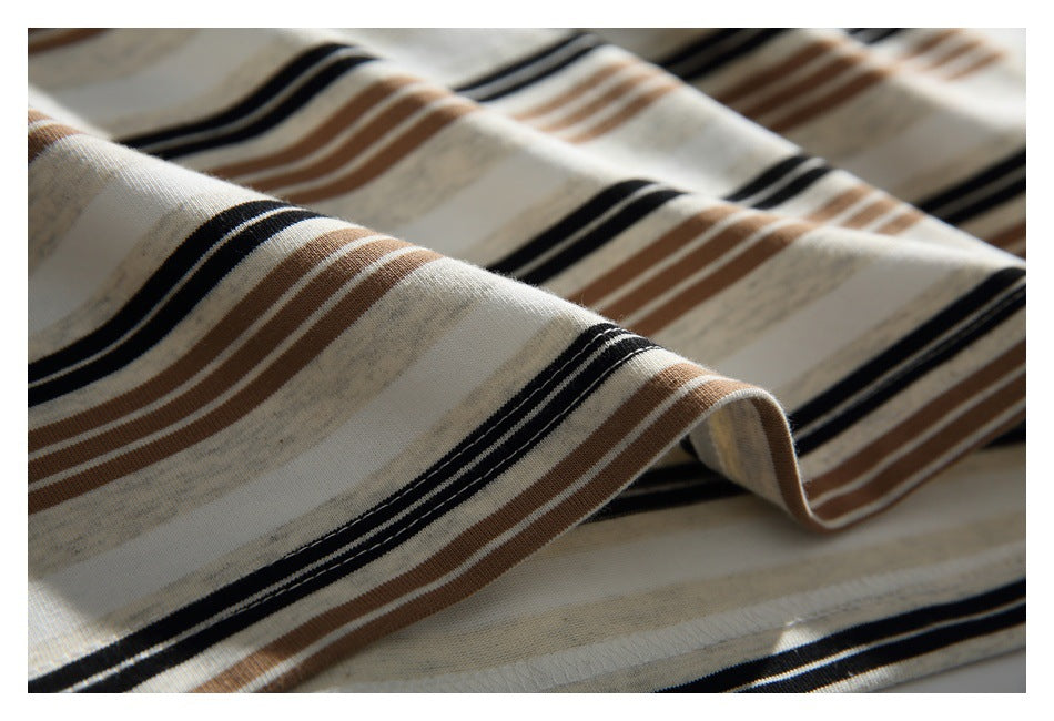 Close-up of cream fabric with alternating black and tan horizontal stripes, draped in soft folds.