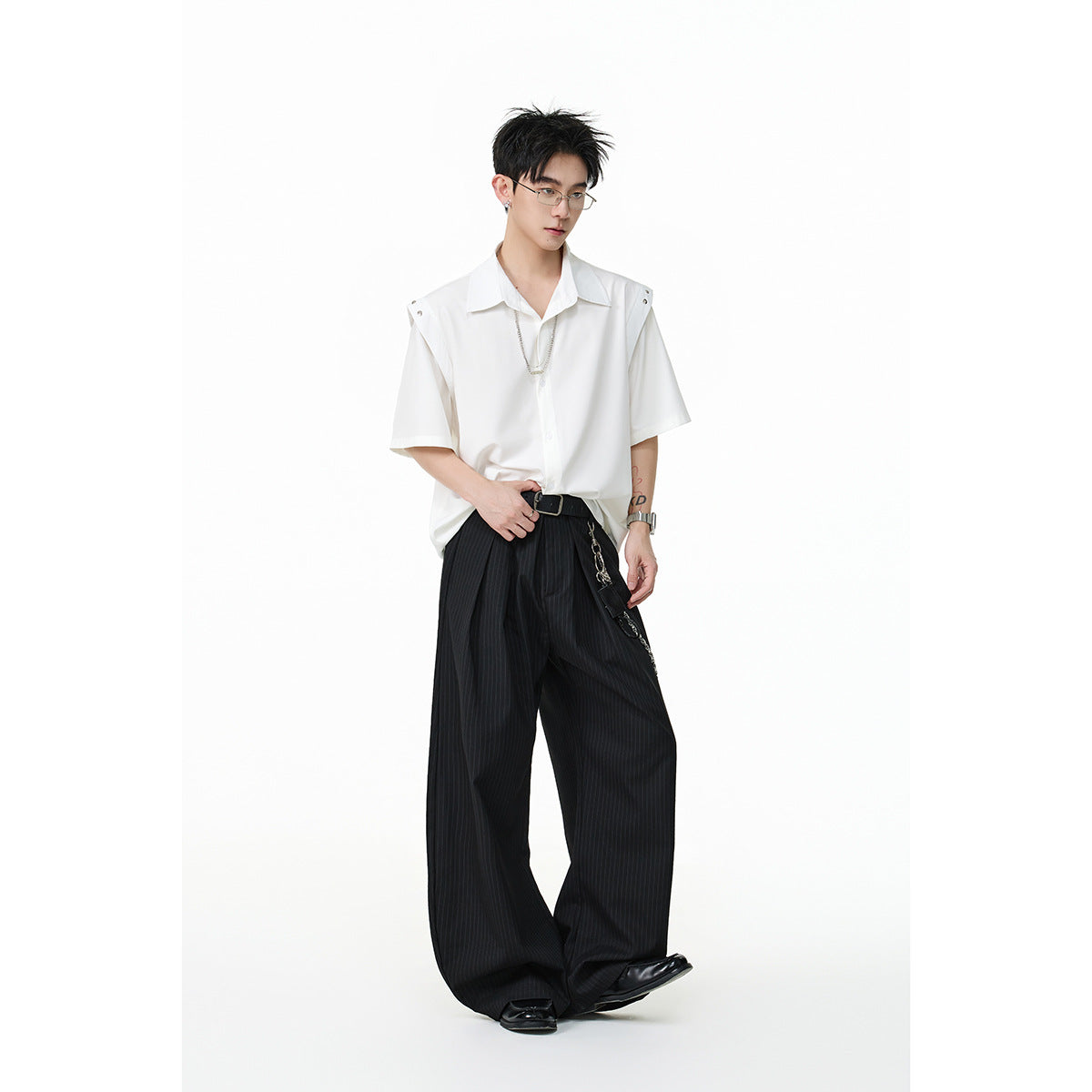 Full-length model wearing a white short-sleeve button-up shirt and wide black pinstripe trousers.