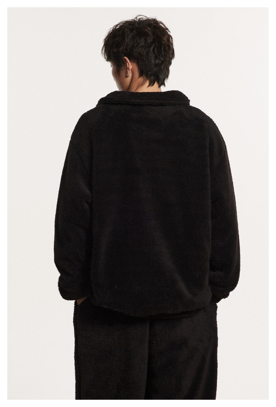 Back view of a model wearing a black plush pullover with a folded collar.