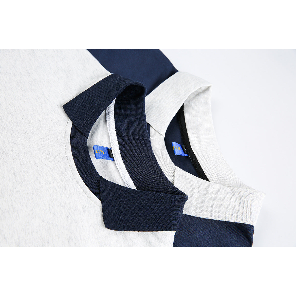 Close-up of overlapping gray and navy polo collars with blue neck labels.