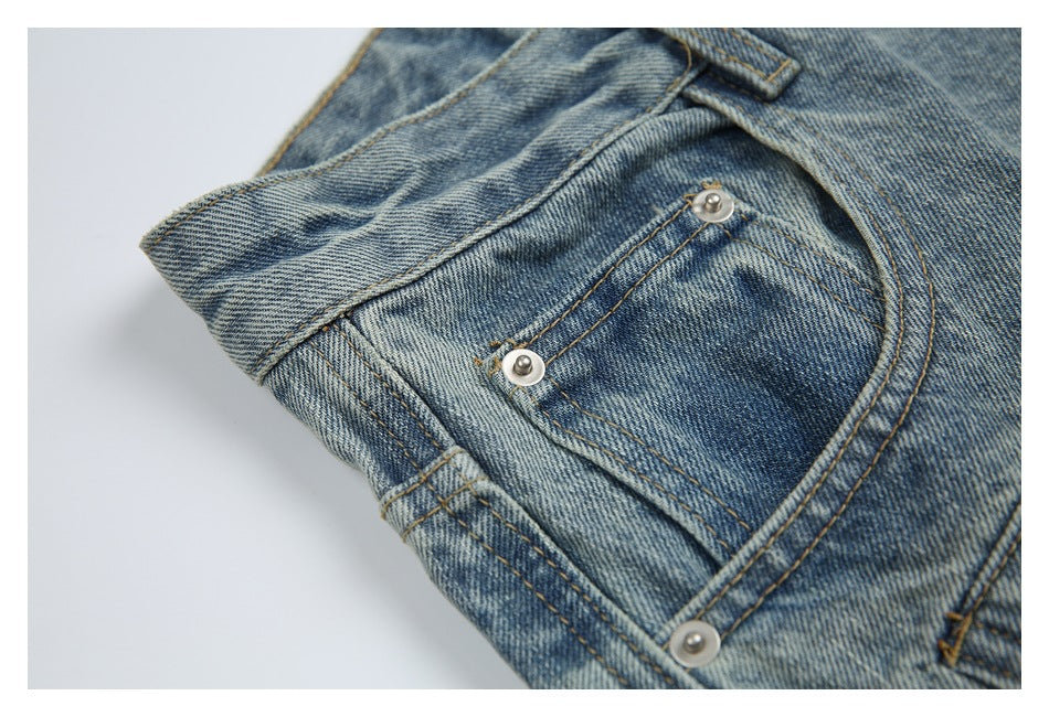 Close-up of the front coin pocket and metal rivets on light blue washed jeans.