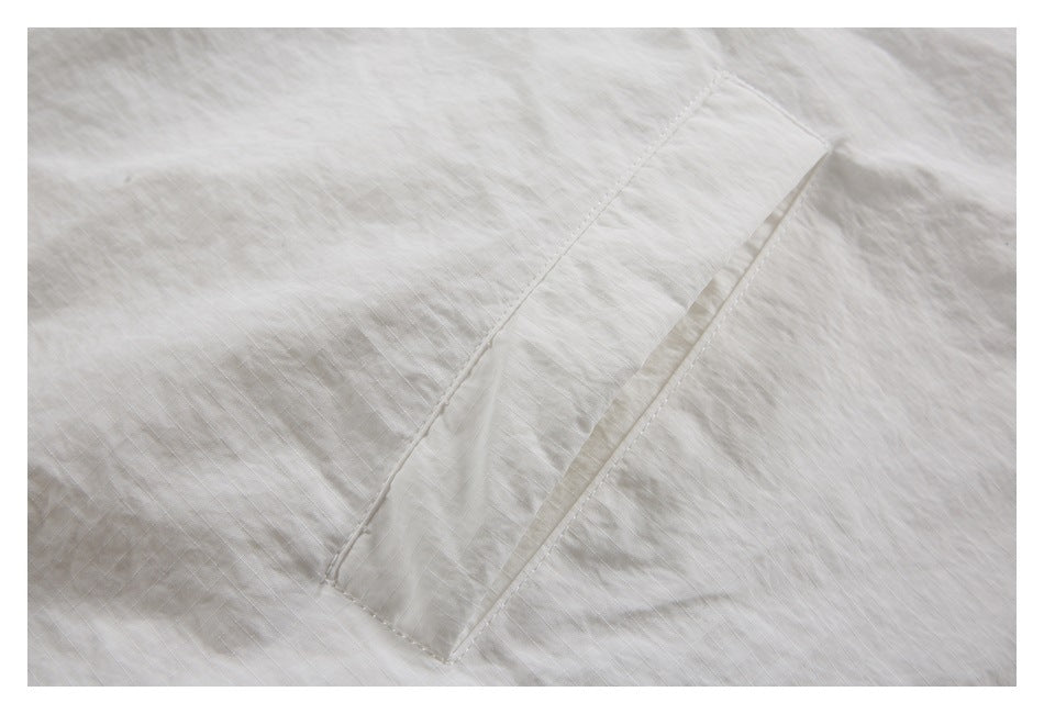 Close-up of a stitched white pocket opening on a lightly textured garment.