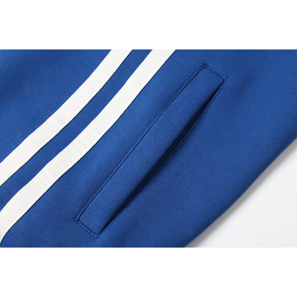 Close-up of a blue jacket’s slanted pocket beside two white stripes.