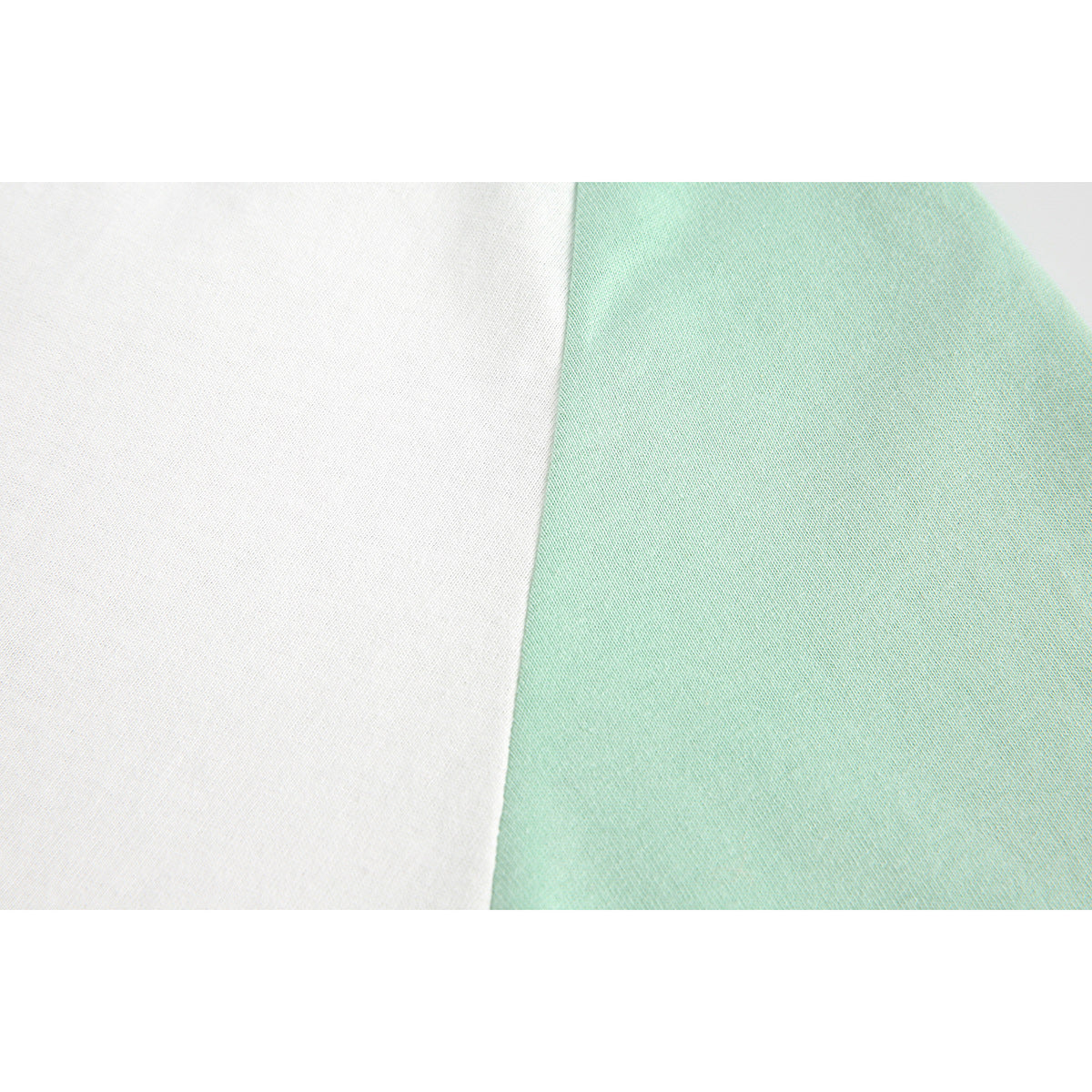 Macro view of white and pale mint fabric panels meeting at a diagonal seam.
