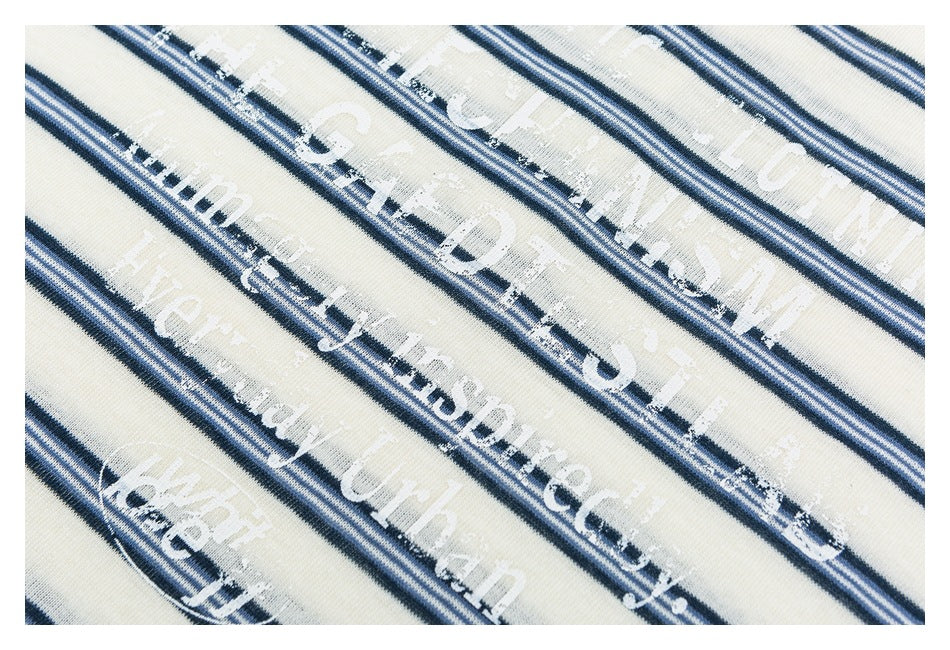 Close-up of distressed white lettering printed over navy and pale blue stripes on ivory fabric.