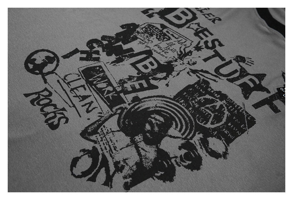 Close-up of a gray garment with a large distressed black collage graphic featuring English lettering and illustrations.