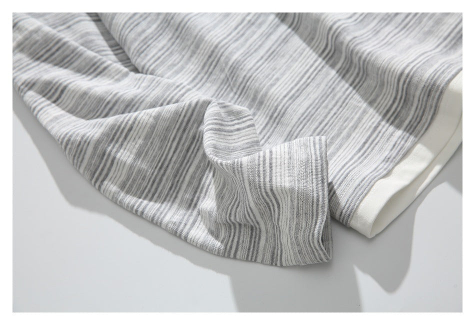 Close-up of the striped sleeve cuff and cream hem edge of a gray-and-white top.