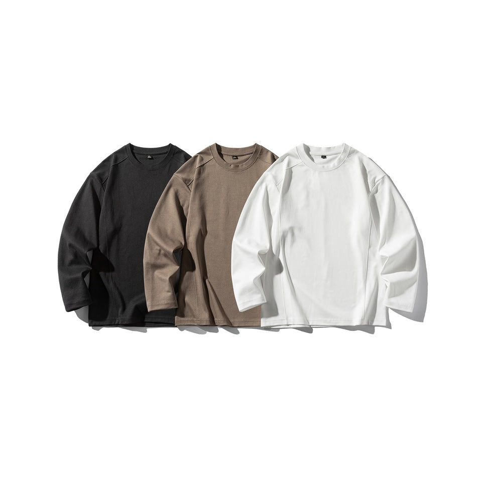 Three long-sleeve crewneck tops displayed together in black, taupe, and white.