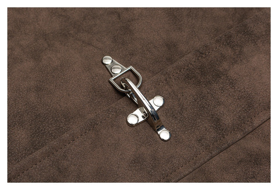 Close-up of a shiny silver-tone clasp fastener on the textured brown jacket fabric.