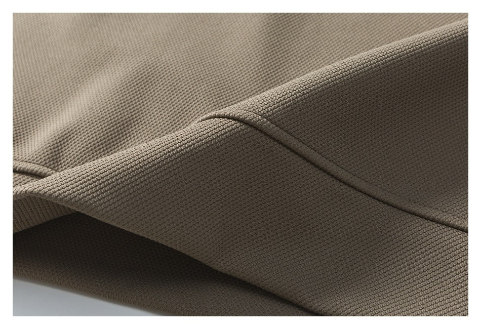 Close-up of taupe textured fabric showing a curved stitched seam and folded edge.